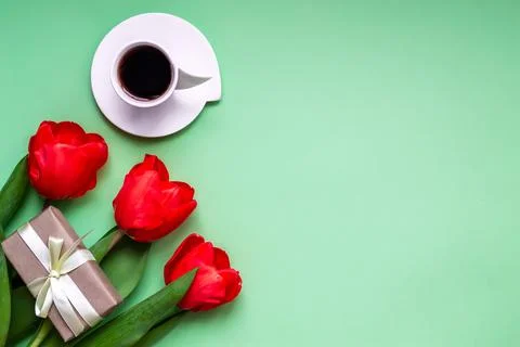 Flat lay, top view festive greeting background. Coffee in a cup and red tulip Stock Photos