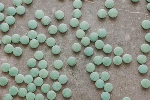Flat lay top view of green spirulina pills scattered on dark slate backgrou.. Stock Photos