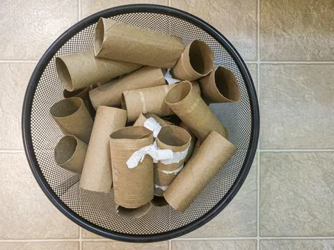 Flat lay top view image of a metal trash bin full of empty toilet paper rolls Stock Photos