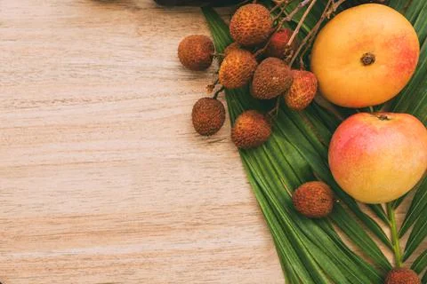 Flat lay, top view, Mix of Exotic fruits and palm leaf on a brown background Stock Photos