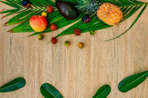 Flat lay, top view, Mix of Exotic fruits and palm leaf on a brown background Stock Photos