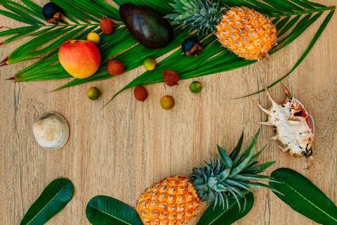 Flat lay, top view, Mix of Exotic fruits and palm leaf on a brown background Stock Photos