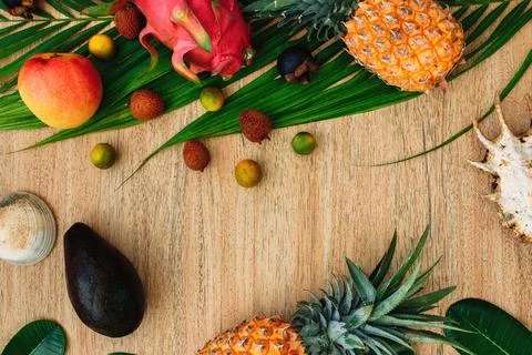 Flat lay, top view, Mix of Exotic fruits and palm leaf on a brown background Stock Photos