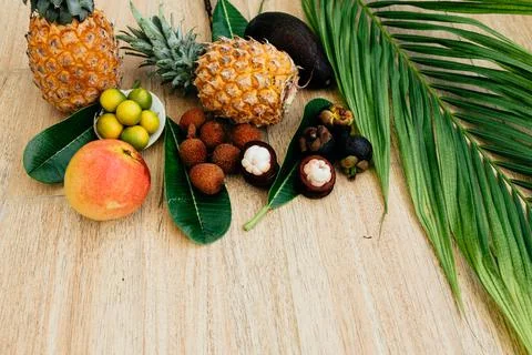 Flat lay, top view, Mix of Exotic fruits and palm leaf on a brown background Stock Photos