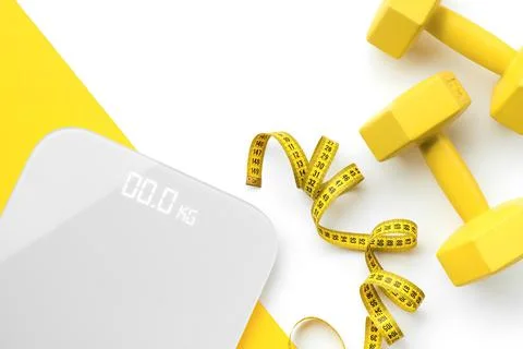 Flat lay top view scales, dumbbell and tape measure on white yellow background 스톡 사진