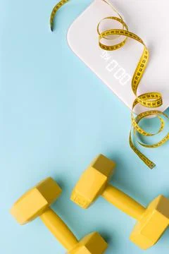 Flat lay top view scales, dumbbell and tape measure on blue background 스톡 사진