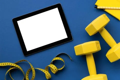 Flat lay top view tablet with yellow sport equipments on classic blue background 스톡 사진