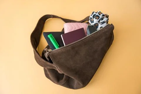 Flat lay of travel essentials in suede bag on pastel background Stock Photos