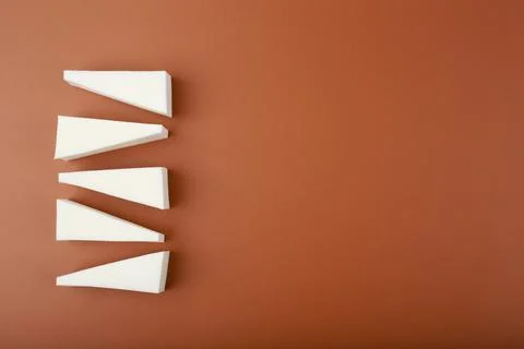 Flat lay with triangle shaped make up sponges on brown background with copy Stock Photos