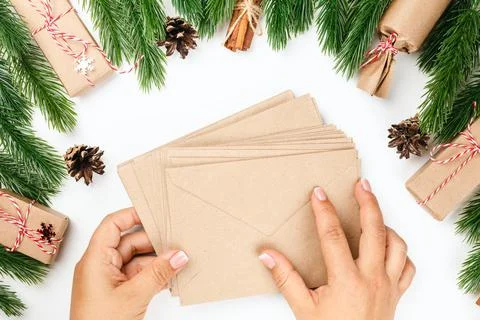 Flat lay of two female hands holding stack of craft paper envelopes for greeting Foto stock