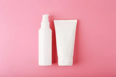 Flat lay with two white cream tubes in the middle of bright pink background Stock Photos