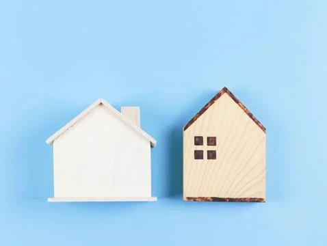 Flat lay of two wooden model houses on blue background. Stock Photos