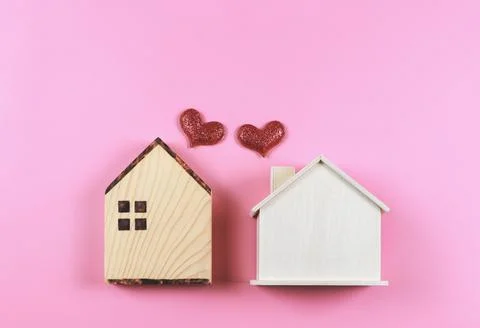 Flat lay of two wooden model houses with red glitter hearts on pink  backgr.. Stock Photos