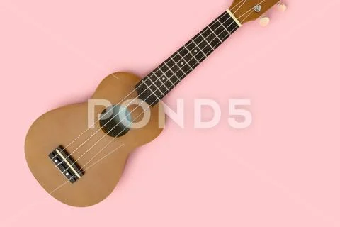 Flat lay of ukulele on a pastel pink background. Stock Photos
