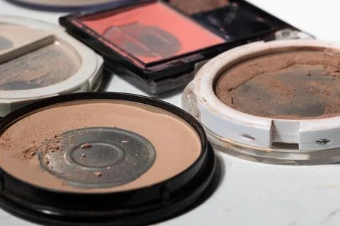 Flat lay of used powder compacts with residue, cracked pans, and dusty surfac Stock Photos