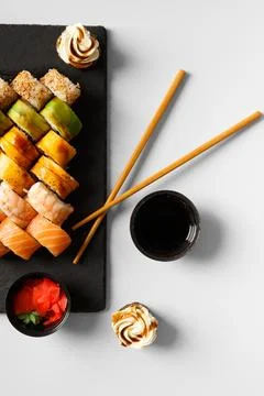 Flat lay of various sushi rolls placed on stone board with chopsticks and s.. Stock Photos
