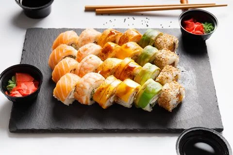 Flat lay of various sushi rolls placed on stone board with chopsticks and s.. Stock Photos