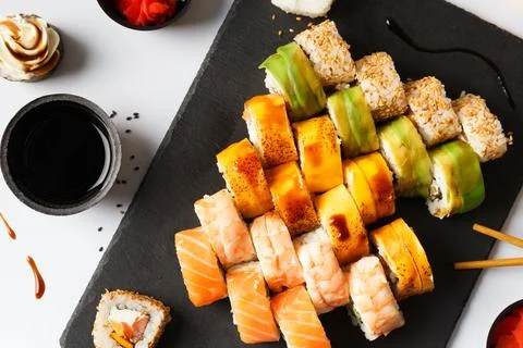 Flat lay of various sushi rolls placed on stone board with chopsticks and s.. Stock Photos