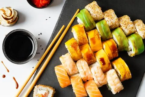 Flat lay of various sushi rolls placed on stone board with chopsticks and s.. Stock Photos
