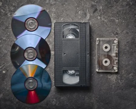 Flat lay video cassettes, CD's, audio cassette on a black concrete surface. R Stock Photos