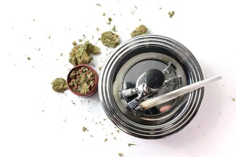 Flat lay view of a cannabis branch, joint and red grinder isolated in a white Stock Photos