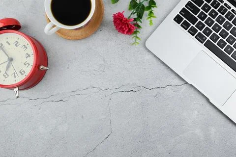 Flat lay view of clock, coffee, flower and laptop with copy space. Stock Photos