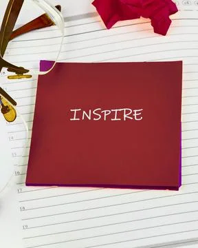 A flat lay view of a crimson note card with the word INSPIRE in white letters Stock Photos