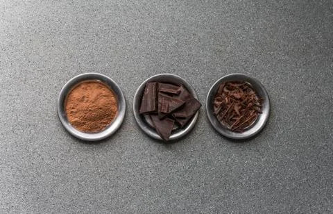 A flat lay view of dark milk chocolate, cocoa powder, and chocolate shavings. Stock Photos