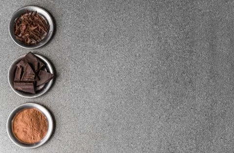 A flat lay view of dark milk chocolate, cocoa powder, and chocolate shavings. Stock Photos