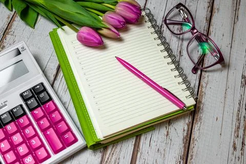 Flat lay view of desktop surface tulips, notepad with calculator on wooden li Stock Photos