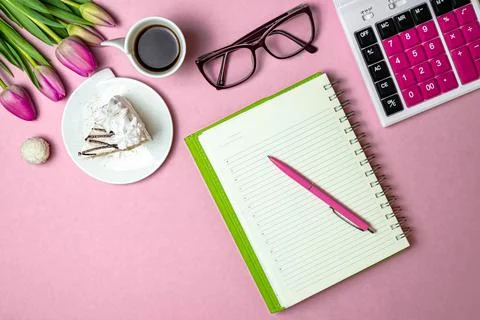 Flat lay view of desktop surface, tulips, coffee with cake and notepad with c Stock Photos
