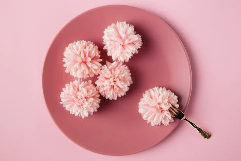 Flat lay view of five flowers  in the pink plate with golden fork. Minimal co Stock Photos