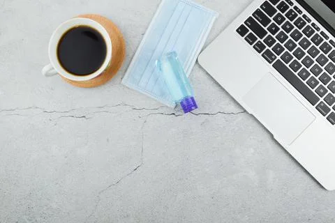 Flat lay view of laptop, face mask, hand sanitizer and a cup of coffee with c Stock Photos