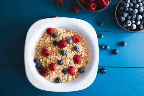 Flat lay view of oat flake with blueberry and raspberry over blue wooden back Photos