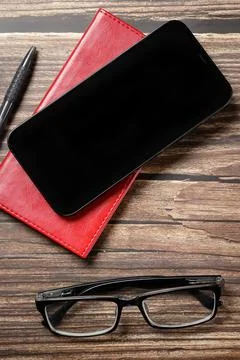 Flat lay view of a red notebook, smartphone, pen on a wooden background. Top Stock Photos
