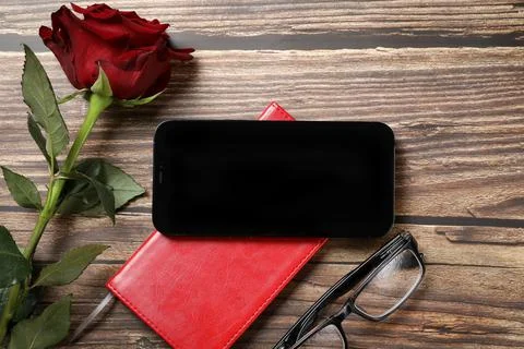 Flat lay view of a red notebook, smartphone, pen on a wooden background. Top Stock Photos