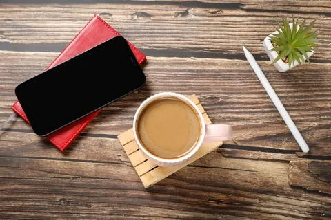 Flat lay view of a red notebook, smartphone, pen on a wooden background. Top Stock Photos