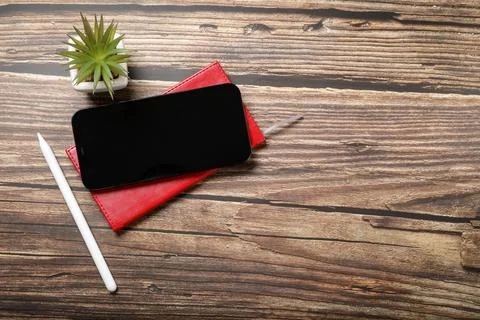 Flat lay view of a red notebook, smartphone, pen on a wooden background. Top Stock Photos