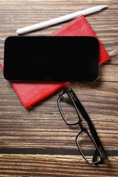 Flat lay view of a red notebook, smartphone, pen on a wooden background. Top  Stock Photos