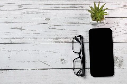Flat lay view of a red notebook, smartphone, pen and black glasses on a white Stock Photos