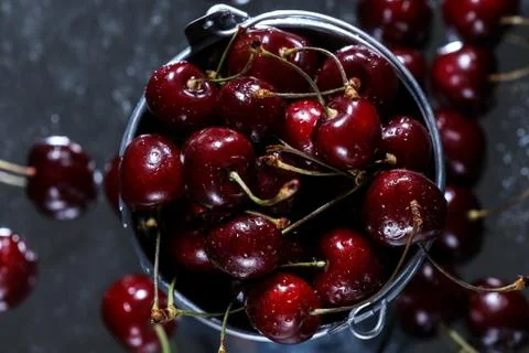 Flat lay view of a red sweet cherries in a metal bucket on a black background. Stock Photos