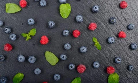 Flat lay view at ripe bilberry and raspberry berries on slate stone tray c... Foto stock