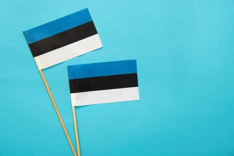 Flat lay view of two small hand held Estonia flags on blue background. Stock Photos