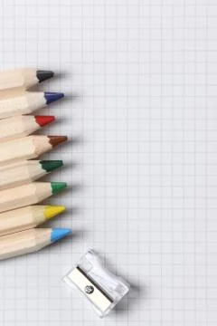 Flat lay view of white notebook , color pencils and pencil sharpener on a table. Stock Photos