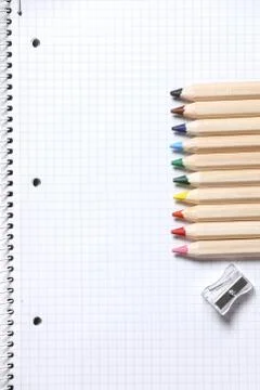 Flat lay view of white notebook , color pencils and pencil sharpener on a table. Stock Photos
