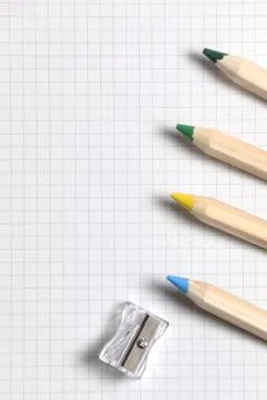 Flat lay view of white notebook , color pencils and pencil sharpener on a table. Stock Photos