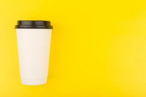 Flat lay with white cardboard cup of coffee on yellow background with copy space Stock Photos