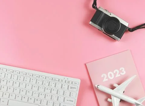 Flat lay of white computer keyboard, pink diary 2023, airplane model  and c.. Stock Photos