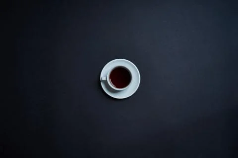 Flat lay of white cup with tea on dark background. Minimalism concept. Stock Photos