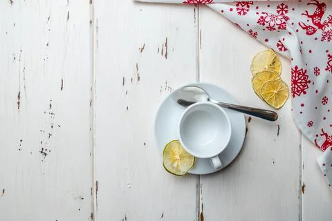 Flat lay. White empty ceramic cup on a saucer and a teaspoon. Dried lime slices. Stock Photos